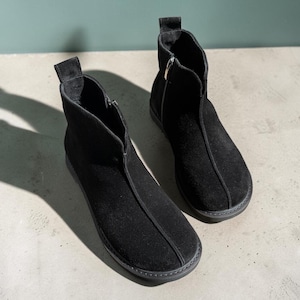 May include: A pair of black suede ankle boots featuring a rounded toe, a vertical seam running down the center of the vamp, a pull tab at the back, and a side zipper closure with a silver-toned circular pull. The boots have a flat black sole.