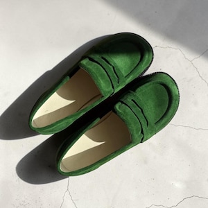Puede incluir: Un par de mocasines de ante verde vibrante con una tira cl&aacute;sica de ranura sobre el empeine, puntera redondeada y una silueta de perfil bajo con un forro interior liso de color claro y una suela de goma oscura y texturizada.