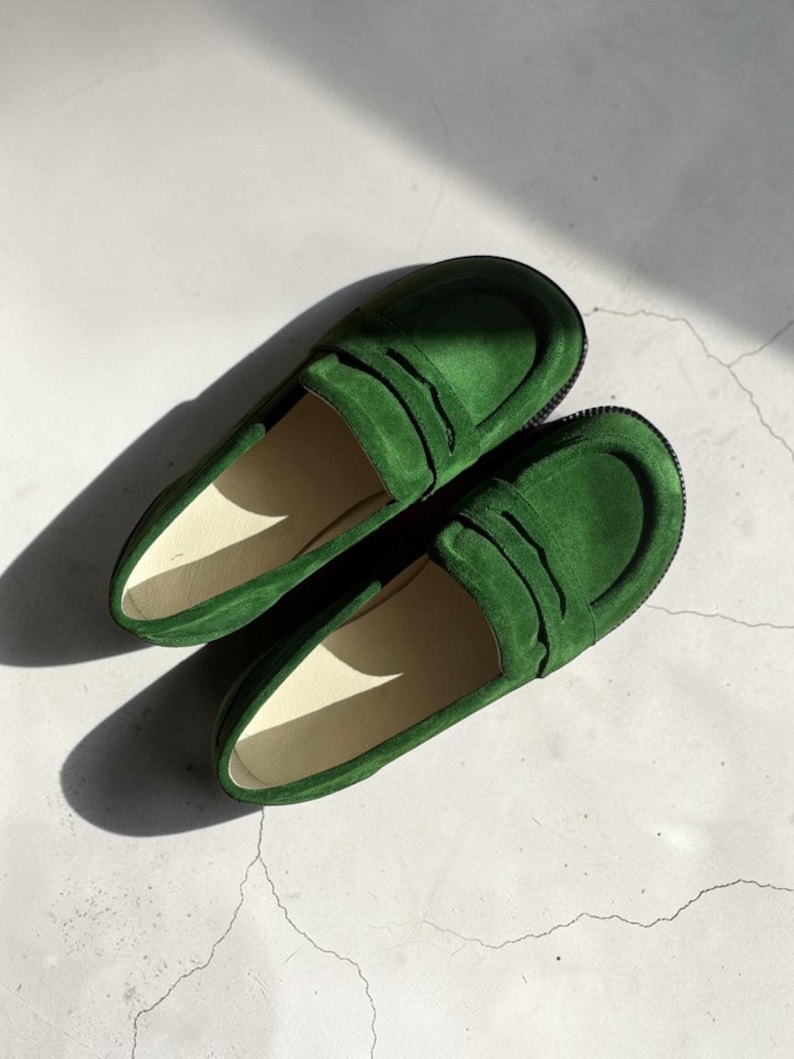 Puede incluir: Un par de mocasines de ante verde vibrante con una tira cl&aacute;sica de ranura sobre el empeine, puntera redondeada y una silueta de perfil bajo con un forro interior liso de color claro y una suela de goma oscura y texturizada.