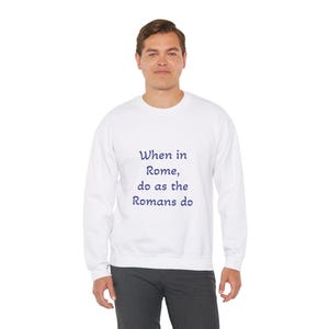 Puede incluir: Sudadera blanca con un estampado de texto azul marino que dice "Cuando estás en Roma, haz como los romanos."