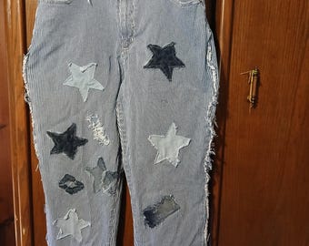 May include: Blue and white striped jeans with star and lip patches. The jeans have a high waist and a relaxed fit. The edges of the jeans are frayed. The jeans are hanging on a white hanger.