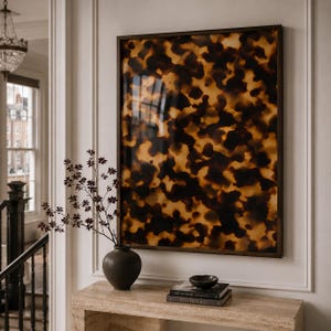May include: A rectangular wall art piece featuring a dark brown and amber tortoiseshell pattern, enclosed in a thin dark wood frame. The artwork displays an abstract, mottled design with organic shapes in varying shades of black, brown, and gold.