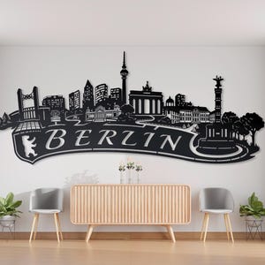 May include: Black metal wall art featuring the Berlin skyline with the text "BERLIN" in a stylised font. The skyline includes iconic landmarks such as the Brandenburg Gate and the Berlin TV Tower.