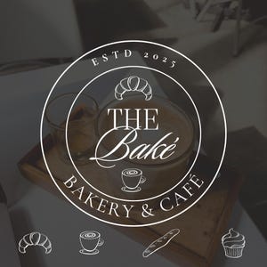 以下が含まれることがあります： 「The Bake Bakery & Cafe」の白いロゴ。コーヒーカップ、クロワッサン、カップケーキのイラストが描かれています。ロゴは円形デザインで、設立日は「ESTD 2025」です。背景はカフェのぼやけた画像です。