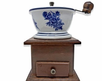 Molinillo de café manual vintage de madera y cerámica con estampado floral azul y manivela, en excelente estado.