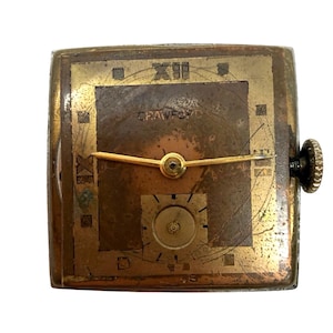 May include: Vintage square-faced watch with a gold-toned metal case. The watch face is a mix of gold and brown tones, with the name "CRAWFORD" visible. Features include gold hands, a small seconds dial, and a textured crown.