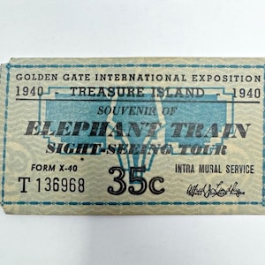 May include: Vintage ticket from the Golden Gate International Exposition in 1940. The ticket is light blue and features text that reads "Elephant Train Sight-Seeing Tour" and "Treasure Island". The ticket also has the price of 35 cents.