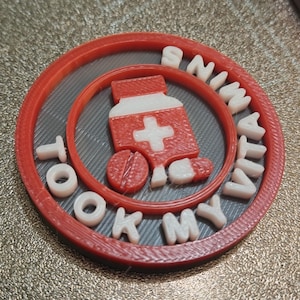 Puede incluir: Un diseño circular rojo y blanco con las palabras "I TOOK MY VITA" en letras blancas. El diseño incluye un frasco de pastillas rojo con una cruz blanca y dos pastillas.