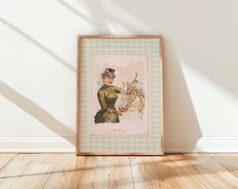 May include: Framed vintage equestrian print featuring a woman in a green riding outfit and top hat, holding the reins of a white horse. The print is set within a light brown wooden frame with a green and white checkered border.