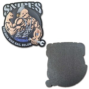 May include: A black and gray patch featuring a muscular cartoon man with a pipe, holding a wrench. The text "SNIPES" is at the top, and "THE MEN WHO SAIL BELOW" is along the bottom. The patch has a textured back.