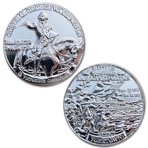 May include: Two silver coins. One coin features General George Washington on horseback with the text "Victorious Commander." The other coin depicts a battle scene with the text "Battles of the American Revolution" and "Siege of Yorktown."