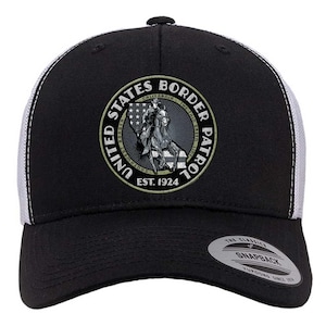 May include: Black and white trucker hat with a circular emblem featuring a rider on horseback, the text "UNITED STATES BORDER PATROL", and "EST. 1924". The hat has a black front panel and brim, with a white mesh back.