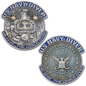 May include: Two US Navy Diver challenge coins. One coin features a diver in a diving helmet with the text "US Navy Diver" and "We Dive The World Over". The other coin has the US Navy emblem.