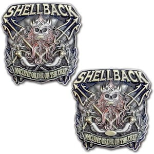 May include: Two silver-colored metal belt buckles with a nautical theme. Each buckle features a skull with a crown, tentacles, crossed tridents, and mermaids. The text "SHELLBACK" and "ANCIENT ORDER OF THE DEEP" are visible.
