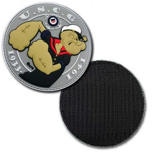May include: A round patch featuring Popeye the Sailor flexing his muscles. The patch has a silver border with the text "U.S.C.G." and the years "1933-1941." Popeye is depicted in his classic sailor outfit with anchor tattoos on his forearms. A black velcro backing is visible.