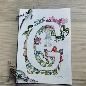 Inicial de acuarela personalizada con hongos, arándanos, corazones y una linda muñeca.
