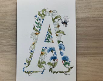May include: A watercolour painting of the letter 'A', adorned with white daisies, blue cornflowers, green leaves, and blueberries. A small bee flies nearby. The artwork is on white paper.
