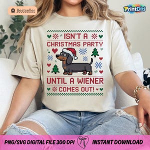 May include: Beige t-shirt with a Christmas-themed design. The design features a dachshund wearing a Santa hat, snowflakes, hearts, and Christmas trees. Text reads "ISN'T A CHRISTMAS PARTY UNTIL A WIENER COMES OUT!"