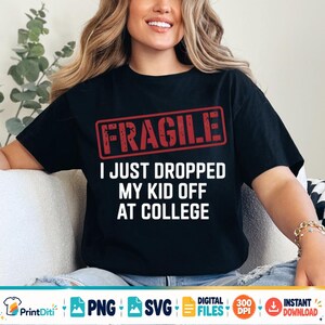 May include: A black short-sleeved t-shirt featuring a red rectangular stamp graphic with the word FRAGILE in distressed lettering. Below the stamp, the white text reads I JUST DROPPED MY KID OFF AT COLLEGE in a bold, sans-serif, capitalized font.