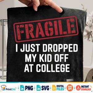 May include: A black blanket featuring a red rectangular stamp graphic with the word FRAGILE in distressed lettering. Below the stamp, white text reads I JUST DROPPED MY KID OFF AT COLLEGE. The fabric has a soft, textured appearance with a small label.