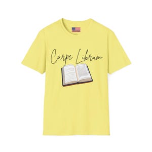 Könnte beinhalten: Ein gelbes T-Shirt mit dem Text "Carpe Librum" und einer Illustration eines offenen Buches.