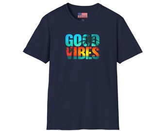 May include: Navy blue t-shirt with the words "GOOD VIBES" in a colorful, tropical-themed design. The text features a gradient of colors, including blue, orange, and yellow, with palm tree silhouettes. A small American flag is visible on the shirt's tag.