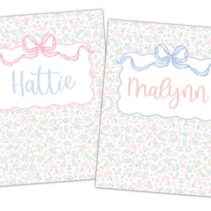 Puede incluir: Dos tarjetas de papelería personalizadas con motivos florales. Una tarjeta tiene un lazo rosa y el nombre "Hattie" en azul claro. La otra tarjeta tiene un lazo azul y el nombre "Malynn" en rosa. Ambas tarjetas tienen un borde blanco festoneado.