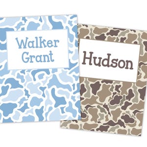 May include: Two personalized cards with camouflage patterns. One card features a blue and white camouflage design with the name "Walker Grant" in blue text. The other card has a brown and tan camouflage pattern with the name "Hudson" in brown text.