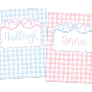 May include: Two personalized notebooks with a gingham pattern. One is light blue with the name "Hadleigh" in cursive, and the other is pink with the name "Annie". Each notebook has a decorative bow and ribbon design.