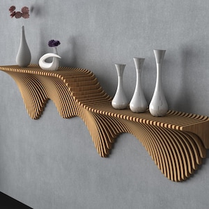 May include: A modern, wooden wall shelf with a unique, wavy design. The shelf holds several white vases and decorative items. The shelf is made of light brown wood and is mounted on a gray wall.