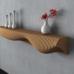 May include: A modern wooden shelf with a unique wave design, mounted on a gray wall. The shelf holds three white vases and a vase with red berries. A tall white vase with branches is in the corner.