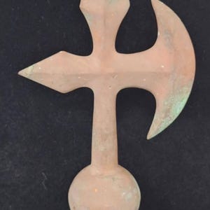 May include: A copper-colored metal weathervane with a cross shape and a crescent moon design. The weathervane has a round ball at the top and a base.