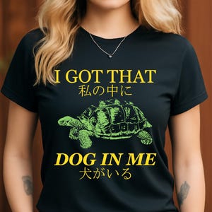 May include: Black t-shirt with the text "I GOT THAT" and "DOG IN ME" in yellow. A green turtle illustration is centered between the text. Japanese text is also included.