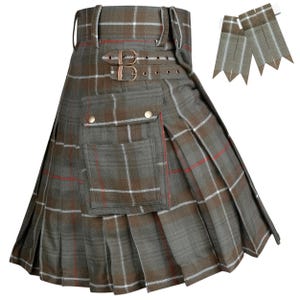 May include: A gray and brown plaid kilt with a pocket and buckle details. The kilt has a pleated design and includes matching plaid flashes. The kilt is a traditional garment.