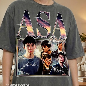 May include: Dark gray comfort color t-shirt featuring a graphic of Asa Butterfield with the name "ASA" in large letters. The shirt has the text "Butterfield" and "COMFORT COLOR PEPPER" printed on it.