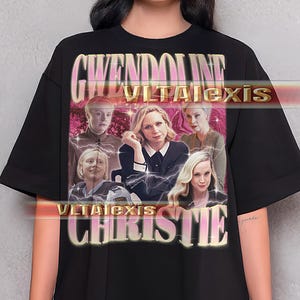 May include: Black t-shirt featuring a graphic of several women with the text "Gwendoline VLTAlexis Christie" in a gold and pink font. The shirt has short sleeves and a crew neck.