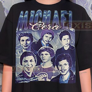 May include: Black t-shirt featuring a graphic of Michael Cera with his name in a retro font. The graphic includes multiple images of the actor. The shirt has a classic crew neck and short sleeves.