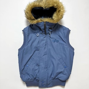 Könnte beinhalten: Eine blaue Weste mit Kapuze mit Kunstfellfutter. Die Weste hat einen Reißverschluss, Knöpfe und ein kleines Logo auf der Brust. Der untere Saum ist gerippt.