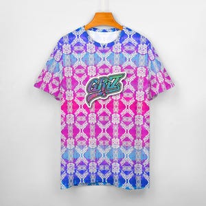 Op de afbeelding: Een wit T-shirt met korte mouwen met een geometrisch patroon in roze, blauw en wit. Het shirt heeft een kleurrijk patch met het woord "GRIZ" op de voorkant.