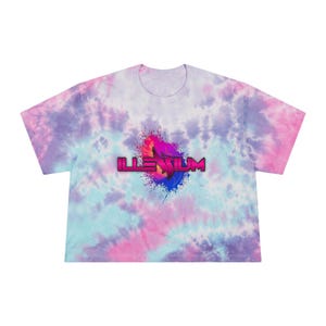 May include: A tie-dye crop top in shades of blue, pink, and purple. The shirt features the word "ILLENIUM" in a pink and purple font with a colorful splash design. The shirt has short sleeves and a crew neck.