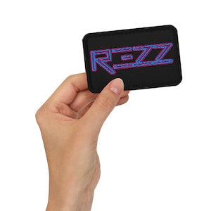 May include: A black patch with the word "REZZ" in blue and pink neon lettering.