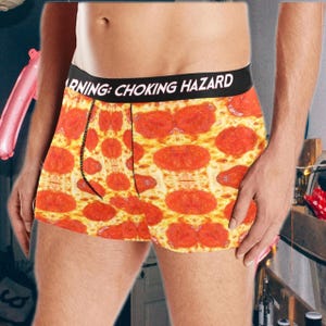 Puede incluir: Bóxers con estampado de pizza de pepperoni. La cintura negra lleva la inscripción blanca "WARNING: CHOKING HAZARD". Un artículo divertido y llamativo.