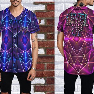 Puede incluir: Una camiseta de b&eacute;isbol de manga corta con un dise&ntilde;o geom&eacute;trico en tonos morado, azul y rosa. La parte delantera presenta un logotipo y la parte trasera muestra las palabras "LEVEL UP" en una fuente estilizada. La camiseta tiene una parte delantera abotonada.