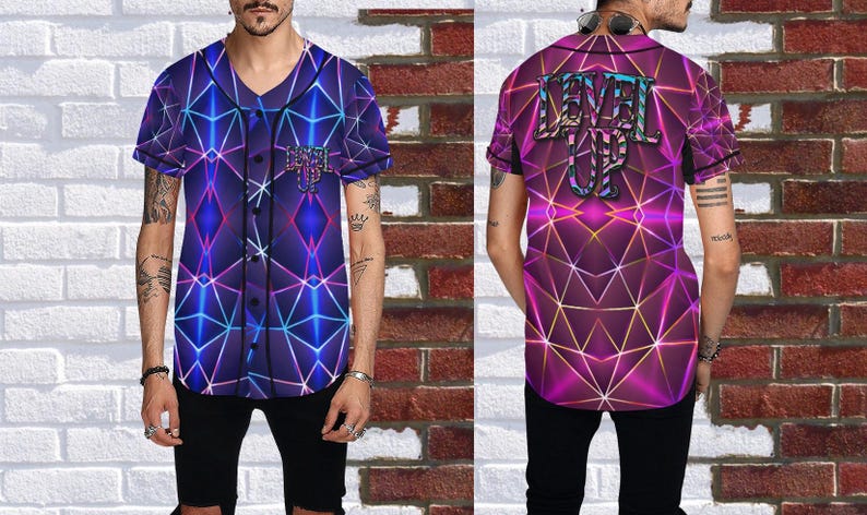 Puede incluir: Una camiseta de b&eacute;isbol de manga corta con un dise&ntilde;o geom&eacute;trico en tonos morado, azul y rosa. La parte delantera presenta un logotipo y la parte trasera muestra las palabras "LEVEL UP" en una fuente estilizada. La camiseta tiene una parte delantera abotonada.