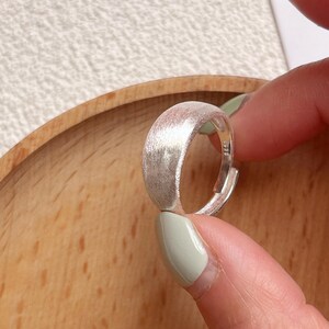 May include: A silver ring with a brushed finish. The ring is simple and elegant, and would make a great gift for any occasion.