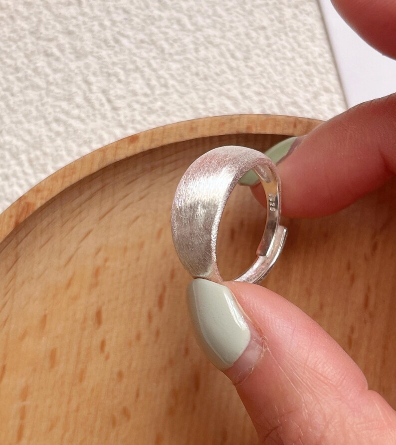 May include: A silver ring with a brushed finish. The ring is simple and elegant, and would make a great gift for any occasion.