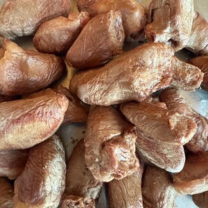 May include: A collection of dried dog treats, with a brown, textured appearance. The treats vary in shape, some being elongated and others more rounded. The overall color is a consistent shade of brown, suggesting a natural product.