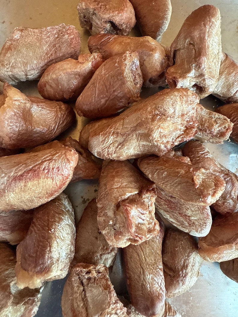 May include: A collection of dried dog treats, with a brown, textured appearance. The treats vary in shape, some being elongated and others more rounded. The overall color is a consistent shade of brown, suggesting a natural product.