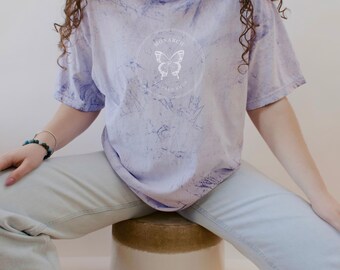 May include: A light purple tie-dye t-shirt with a white circle graphic featuring a butterfly and the text "Monarch Vintage Shop".