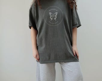 May include: A dark gray oversized t-shirt with a white butterfly graphic and the text "MONARCH MOCKUP SHOP" in a circle.